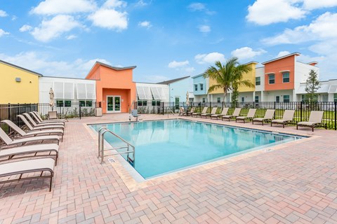 a swimming pool with chairs and buildings in the background